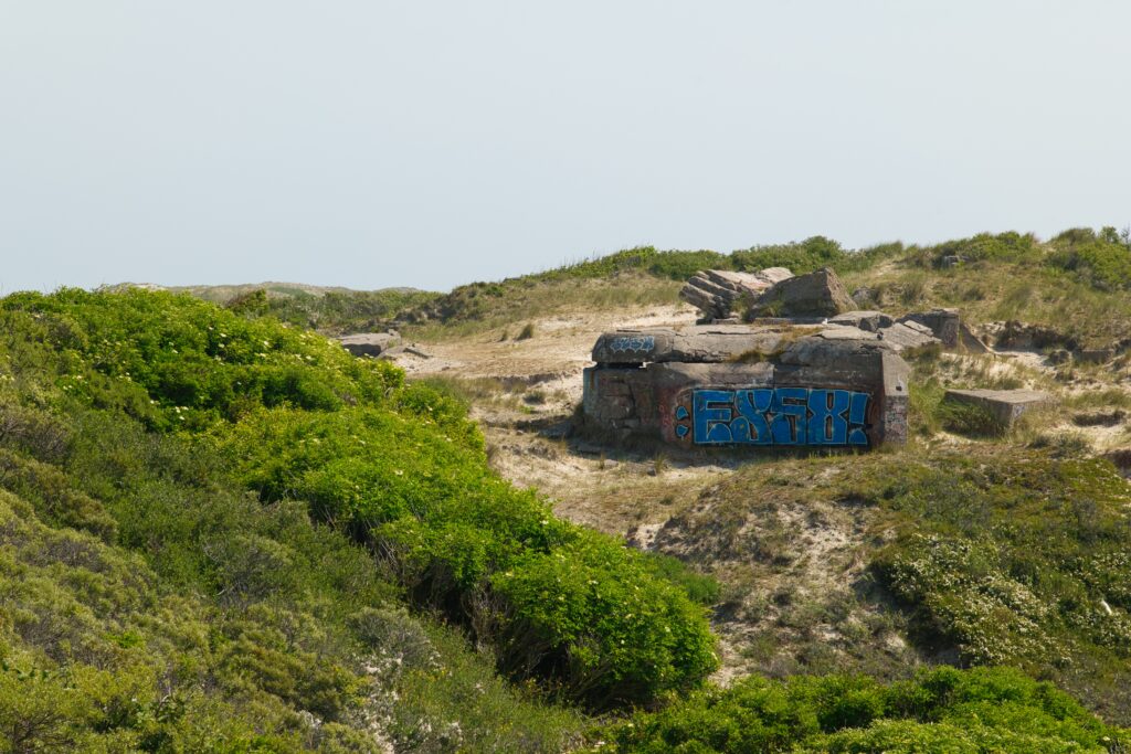 Verwitterte und mit Graffiti verzierter Bunker in einer Düne